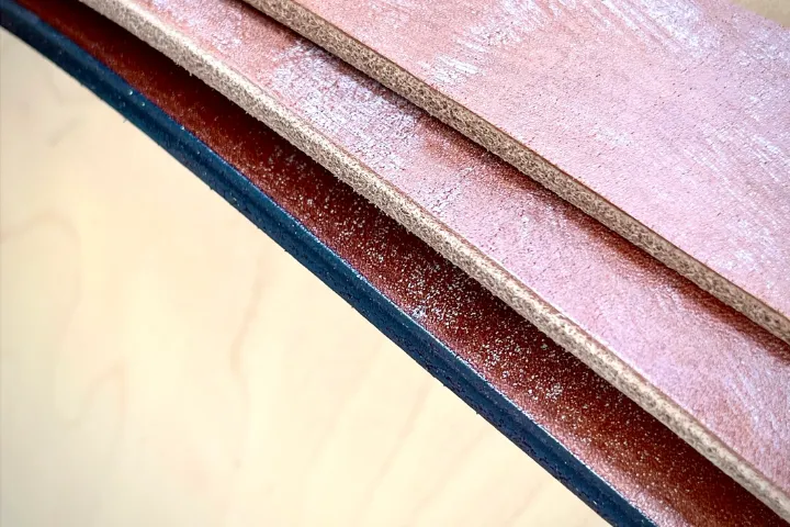 a close up comparison of a finished, burnished leather belt edge versus a raw, frayed edge.